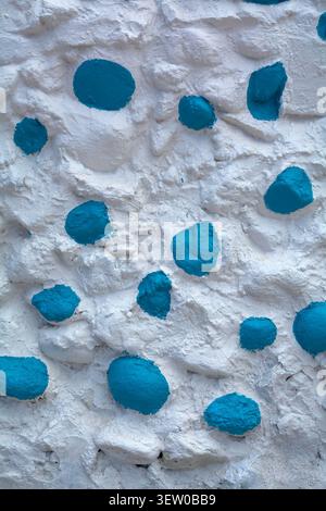 Abstract architectural pattern background showing a detail of traditional whitewashed stucco wall with colorful painted stones and copy space. Stock Photo