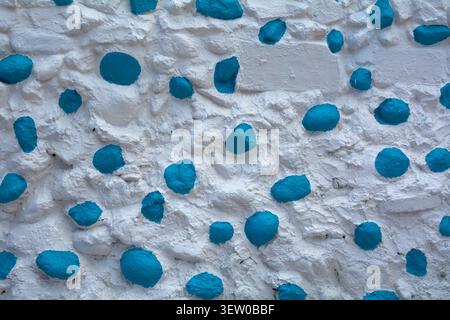 Abstract Mediterranean architectural background texture showcasing traditional white wash and colorful painted stone patterns with copy space. Stock Photo