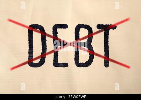 Word Debt written and crossed out on paper Stock Photo