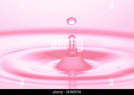 Splash of water with drop, closeup. Toned in pink Stock Photo