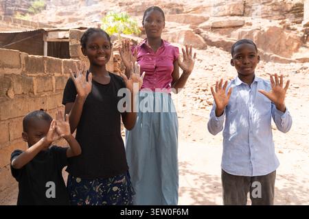 With their hands lifted high and covered in soap, the children wait patiently for their mother to bring clean water for rinsing. Stock Photo