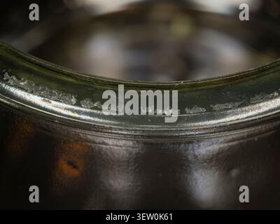 Macro close up of a worn metallic rim with peeling chrome plating on a curved dark vintage object, textured industrial detail Stock Photo