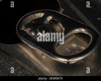 Macro extreme close up of an opened aluminum beverage can tab showing the ring pull mechanism and texture of the metallic top Stock Photo