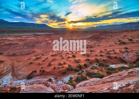 Sunset Over Red Sandstone Desert Landscape With Mountains And Dramatic Sky Stock Photo