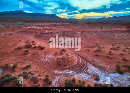 Red Desert Landscape with ATV Tracks and Colorful Sunset Sky Stock Photo