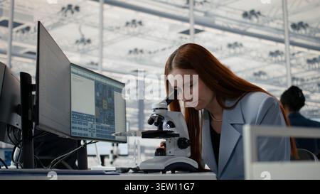 Studying microchip architecture, microscope and woman in microelectronics development facility. Researching semiconductor materials, microscopy tool and female engineer in office, camera A close up Stock Photo