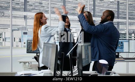 Happy multiethnic engineering team in microchip factory office celebrate project completion, achieving milestones. Cheerful colleagues excited by scientific breakthrough in semiconductor lab, camera A Stock Photo