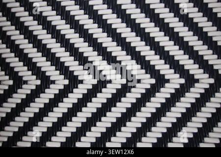 Close view of black and white synthetic woven material featuring geometric chevron pattern and repeating texture. Stock Photo