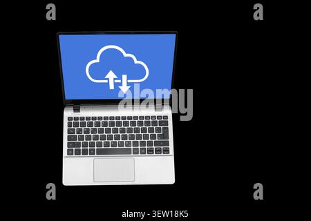 A laptop sits on a flat surface with a blue screen displaying a cloud symbol. The cloud features arrows pointing up and down, indicating data transfer Stock Photo