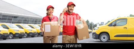 Delivery workers holding packages with vans in the background Stock Photo