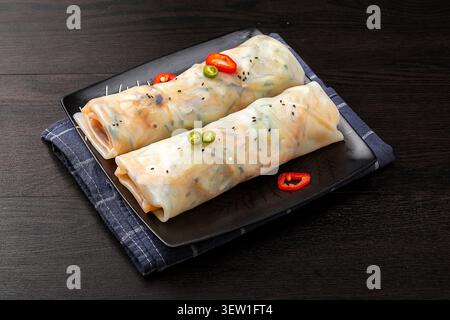 Yunnan style fresh rice sheets wrapped with mixed vegetables on a black square plate Stock Photo