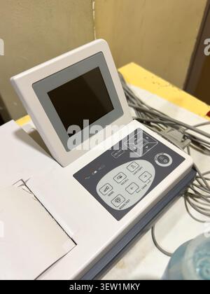 portable medical ecg machine with blank screen and button control panel, diagnostic cardiology equipment on table, close up soft focus view Stock Photo