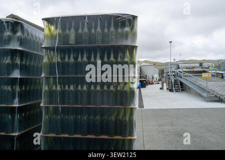 Stacks of empty wine bottles wrapped in plastic outside a winery facility represent the scale of Marlborough's world-famous wine industry. Stock Photo