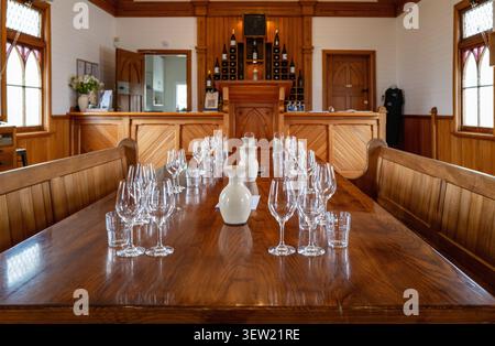 Wine tasting setup with empty glasses on a long wooden table in a rustic cellar door showroom in Marlborough. Stock Photo