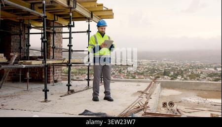 Man, scaffolding and construction worker on site with tablet for email feedback on renovation. Digital technology, infrastructure and civil engineer Stock Photo