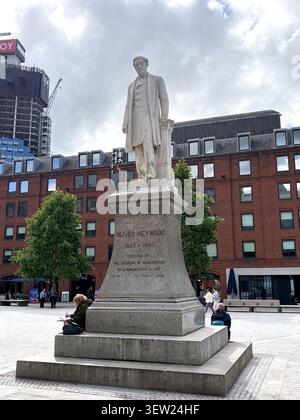 The Oliver Heywood stone statue in Albert Square, Manchester, UK, standing before Victorian red brick architecture in a public plaza. Stock Photo