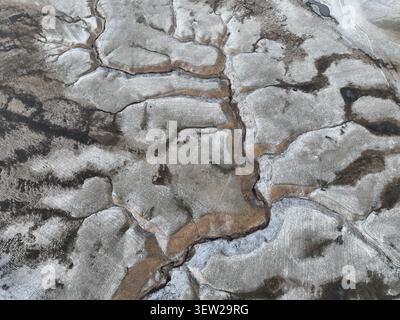 Aerial view of the snow-covered landscape of Castelluccio with intricate patterns of frozen ground and winding streams in the Sibillini Mountains, Cas Stock Photo