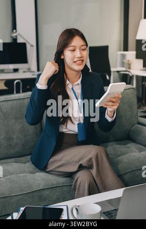 Asian businesswoman sitting at work using laptop talking and consulting in office Stock Photo