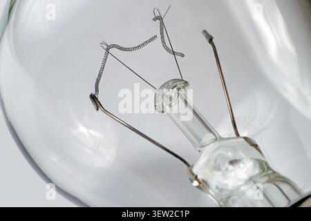 Burned-out incandescent light bulb on a gray background. Burnt tungsten filament close-up. Stock Photo