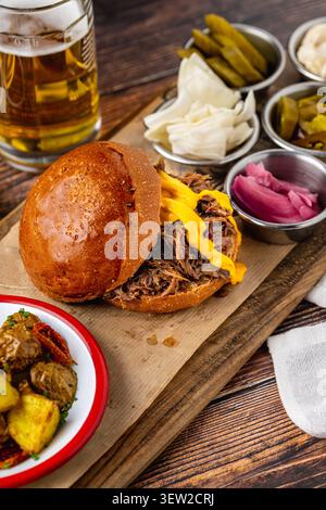 Slow cooked pulled rib beef burger with melted cheese and sides Stock Photo