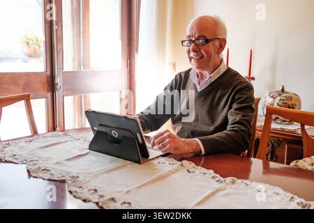 Happy elderly man communicating online with loved ones from home Stock Photo
