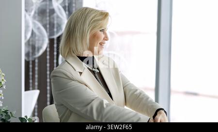 Smiling Woman With Professional Demeanor. Professional Woman In Blazer With Serene Expression By Window. Confident Woman Dressed In Blazer Smiling Stock Photo