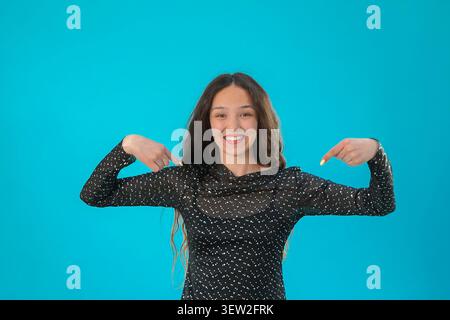 Woman pointing at herself with both index fingers and smiling at the camera  Stock Photo