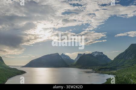 Dramatic sun rays breaking through summer clouds over the mountains and fjord of Bergsbotnen Stock Photo