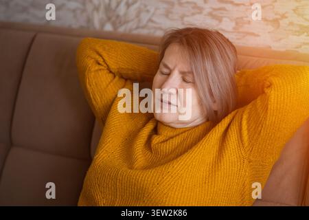 Senior woman relaxing on couch enjoying peaceful rest Stock Photo