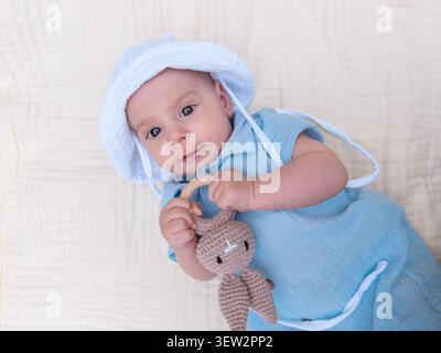 Baby in blue outfit holding knitted bunny toy Stock Photo