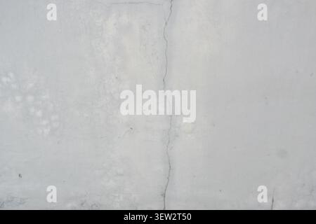 Landscape-orientation close-up of a white plaster wall showing a prominent vertical crack alongside a rectangular patched repair section. Stock Photo
