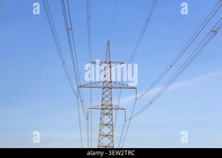 High voltage power transmission tower against blue sky Stock Photo
