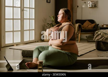Plus Size Woman Practicing Mindful Breathing during Home Yoga Session Stock Photo