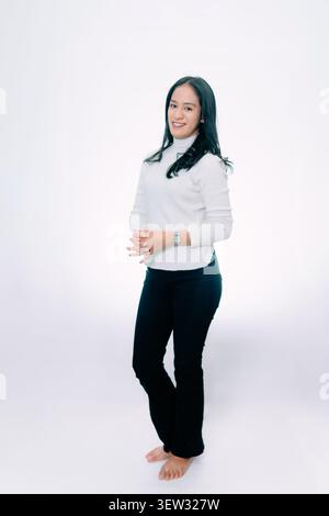 Smiling Asian Woman Posing with Interlocked Fingers on White Background Stock Photo