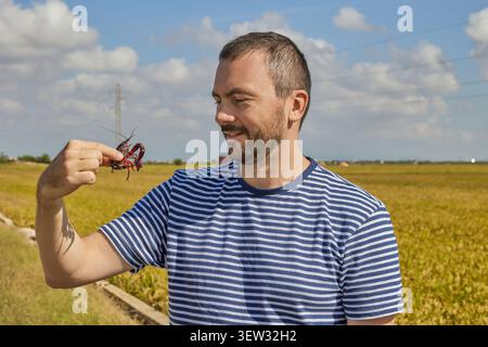 A young man looks at a red swamp crayfish caught in a rice field in Albufera, Valencia, Spain. Stock Photo