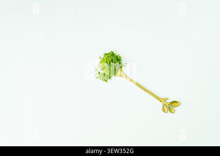 Premium matcha green tea powder on golden spoon on white background. Creative healthy matcha tea concept. Trendy drink idea. Matcha aesthetic. Stock Photo