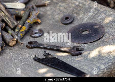 A rusty hand tool and mechanical grinding parts lie on a textured gray background, symbolizing the ongoing process of manual maintenance, hardware rep Stock Photo