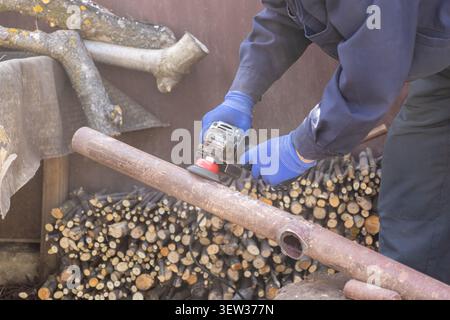 A person wears protective blue gloves while using an electric tool to polish a metal tube, emphasizing professionalism and safety during DIY repair pr Stock Photo