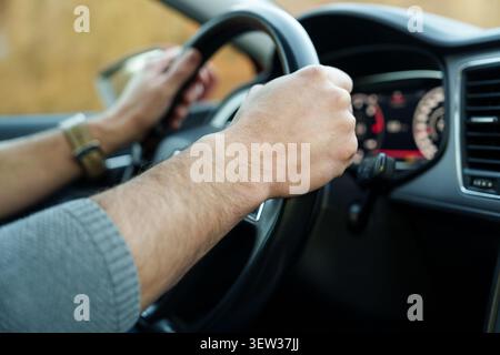 Male hands holding steering wheel while driving Stock Photo