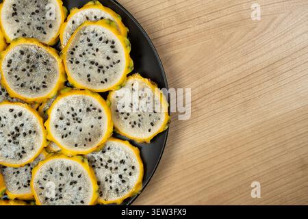 Sliced yellow dragon fruit on black plate with copy space. Stock Photo