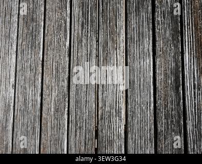 Close up of heavily weathered wood board surface with raised grain, gaps between planks, and visible ground showing through Stock Photo
