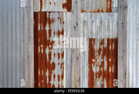 Close up of overlapping reclaimed corrugated tin panels with heavy rust on some panels, silvery gray panels, natural patina seam boards Stock Photo
