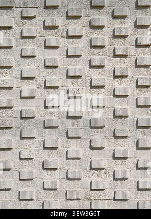 Vertical close up of a painted cream 3D brick wall surface with protruding bricks in a grid pattern Stock Photo