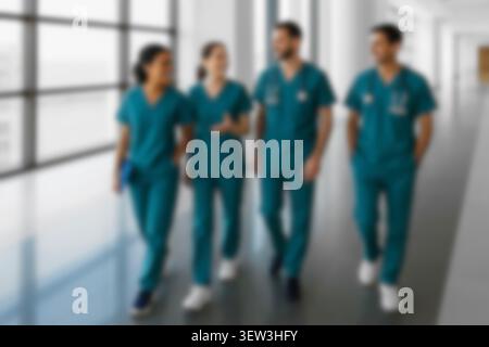 Blurred healthcare team walking in a hospital hallway. Diverse confident doctors, nurses in scrubs smiling, collaborating, and discussing patient care Stock Photo