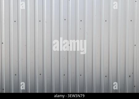 White corrugated metal wall with screws and vertical lines as clean texture background Stock Photo