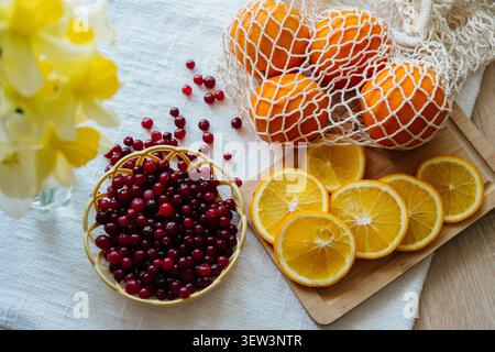 A vibrant flat lay composition featuring fresh whole oranges in a string bag, sliced orange rounds on a wooden board, Stock Photo