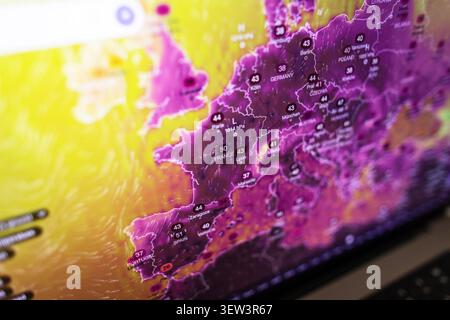 Close-up of a laptop screen showing a weather map with extreme heatwave temperatures in Europe, highlighting global warming, environmental crisis, and Stock Photo
