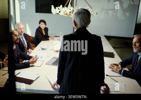 Senior businesswoman leading oil industry boardroom meeting, presenting strategy to diverse executive team and reviewing reports. Ideal for energy leadership, corporate planning, investment use Stock Photo