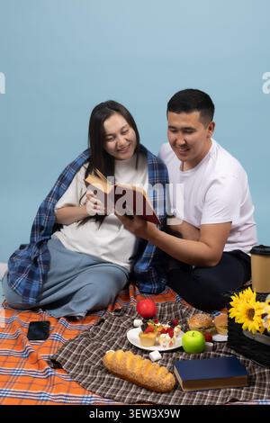 Young man playing acoustic guitar for his girlfriend during home picnic Stock Photo