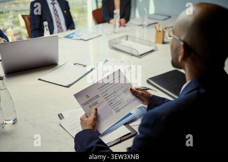 Wide angle view of diverse business team reviewing oil transportation report during boardroom meeting, discussing logistics strategy and energy investment use for corporate presentations Stock Photo